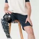 Bionic Limbs - Man in White Shirt and Black Shorts Sitting on Brown Chair