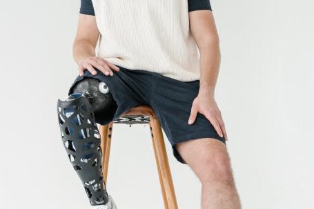 Bionic Limbs - Man in White Shirt and Black Shorts Sitting on Brown Chair