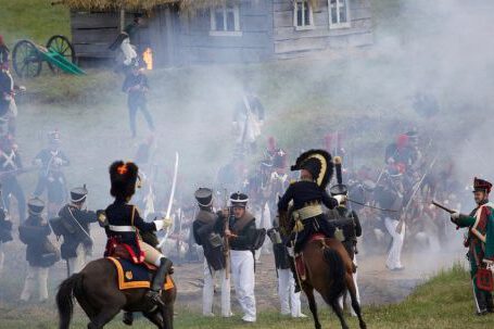 Napoleonic War - Horse mounted officers and soldiers with rifles and muskets fighting on field in countryside during reenactment of Napoleonic war